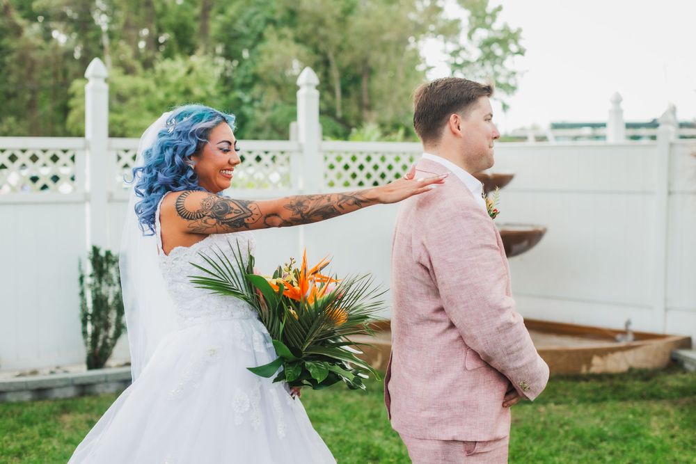 A playful wedding moment with a bride holding tropical flowers and wearing a white dress.