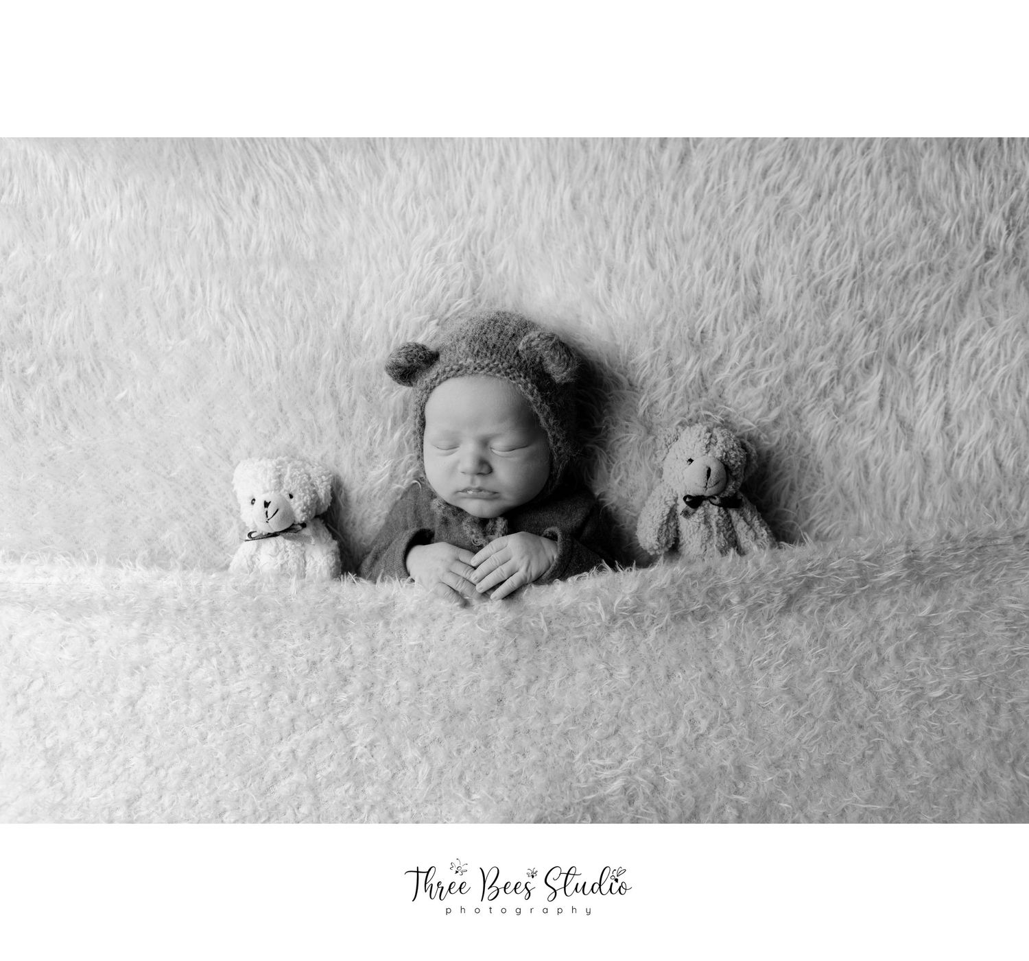 Black and white newborn photography with soft textures and plush toys creating a cozy scene.