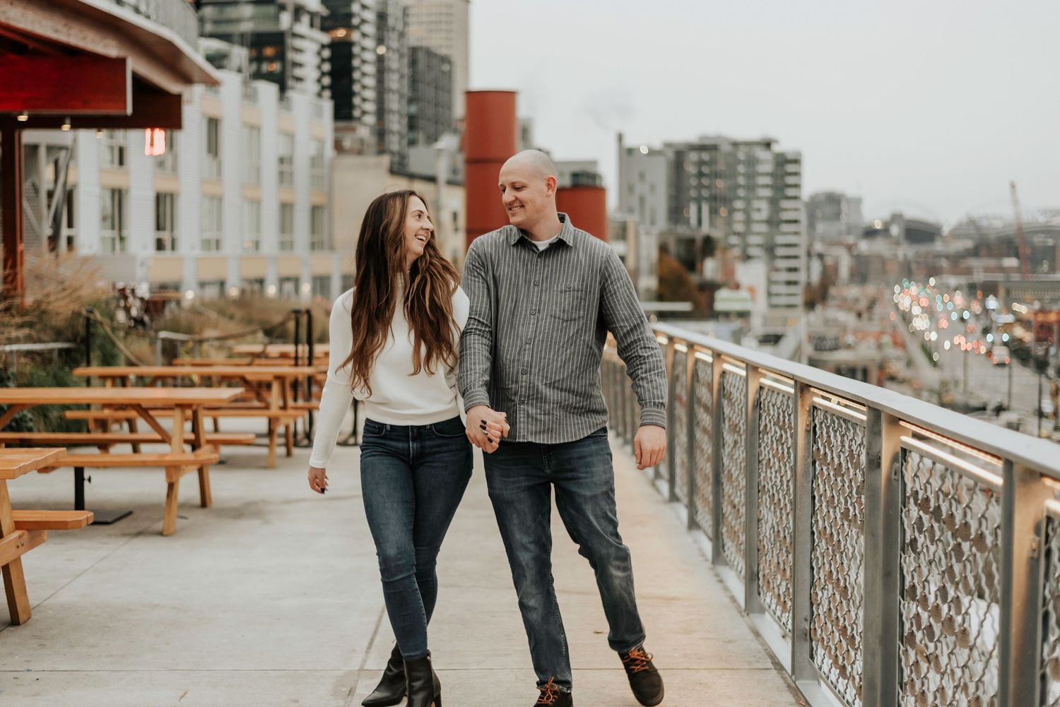 A couple enjoying a romantic walk on an urban rooftop terrace with city views.