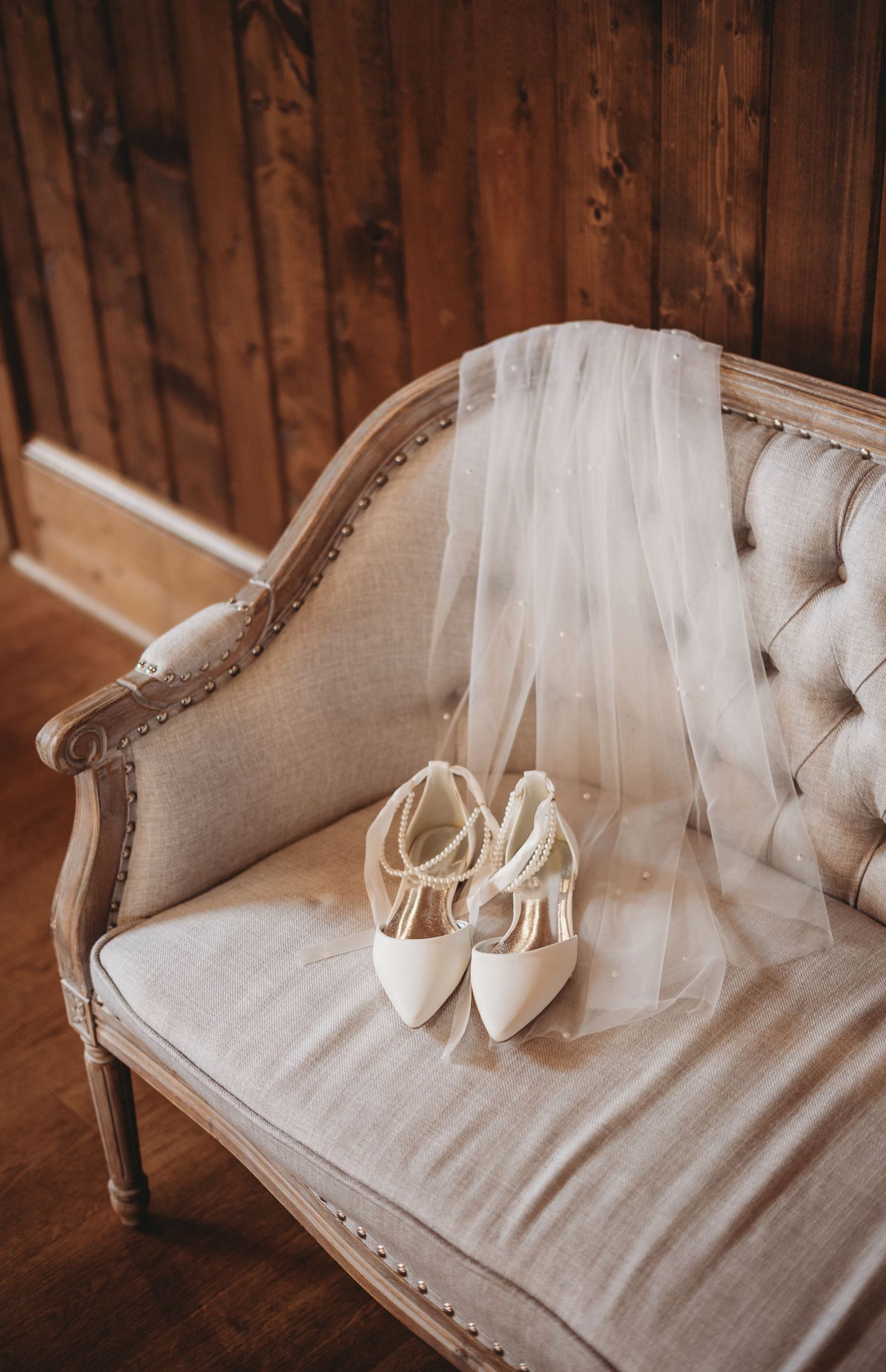 Elegant white bridal heels displayed on a vintage upholstered chair.