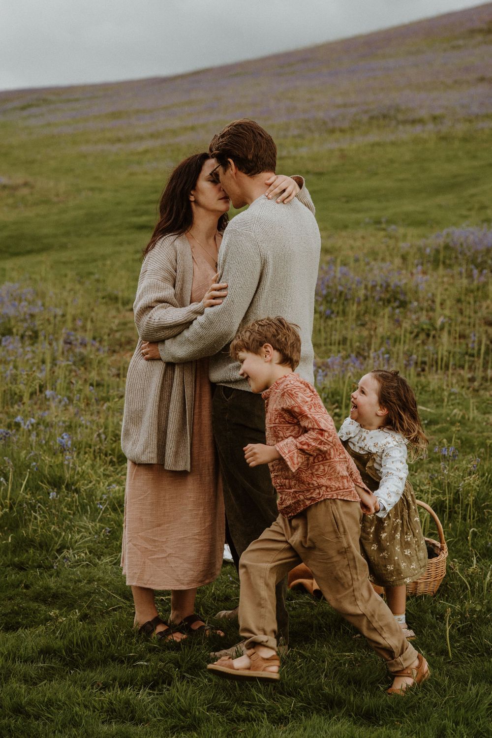 children play whilst their parents have intimate moment in the bluebell hills in Dursley