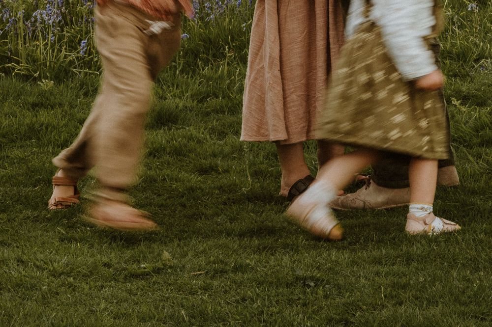 childrens feet run around their parents in cotswold field