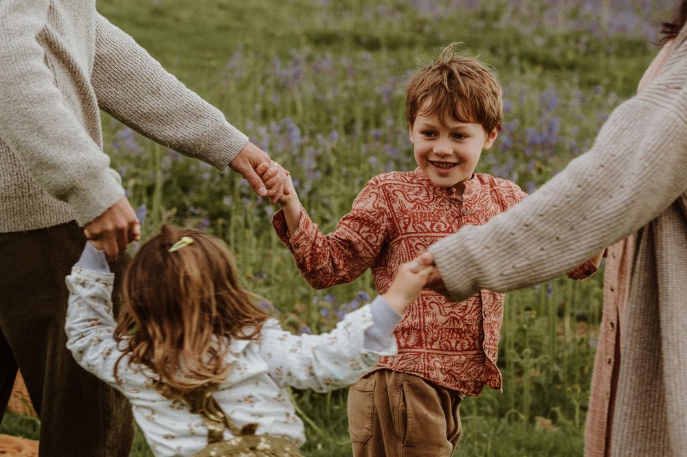 family playing ring o roses during photoshoot on cam peak, during bluebell season