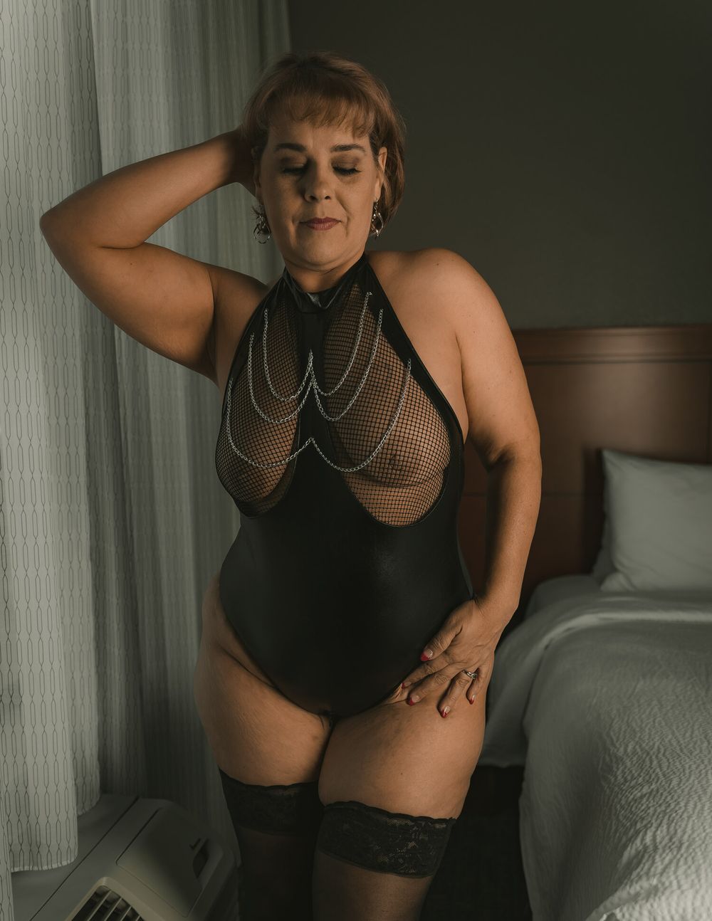 Intimate boudoir photography featuring black mesh bodysuit and delicate jewelry.