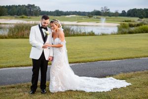 A bride and groom share an intimate moment on a golf course path with water views.