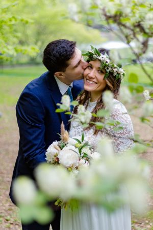Romantic wedding moment captured through spring foliage in a garden setting.