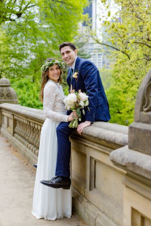 A wedding couple stands against the Manhattan skyline on a cloudy day at Liberty State Park.