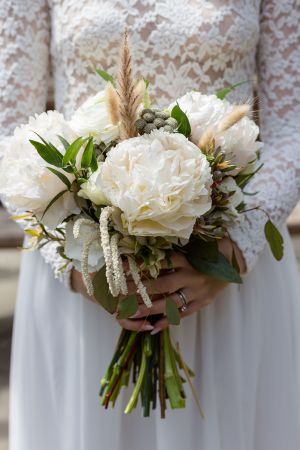 Elegant white peony wedding bouquet with greenery and delicate floral accents.
