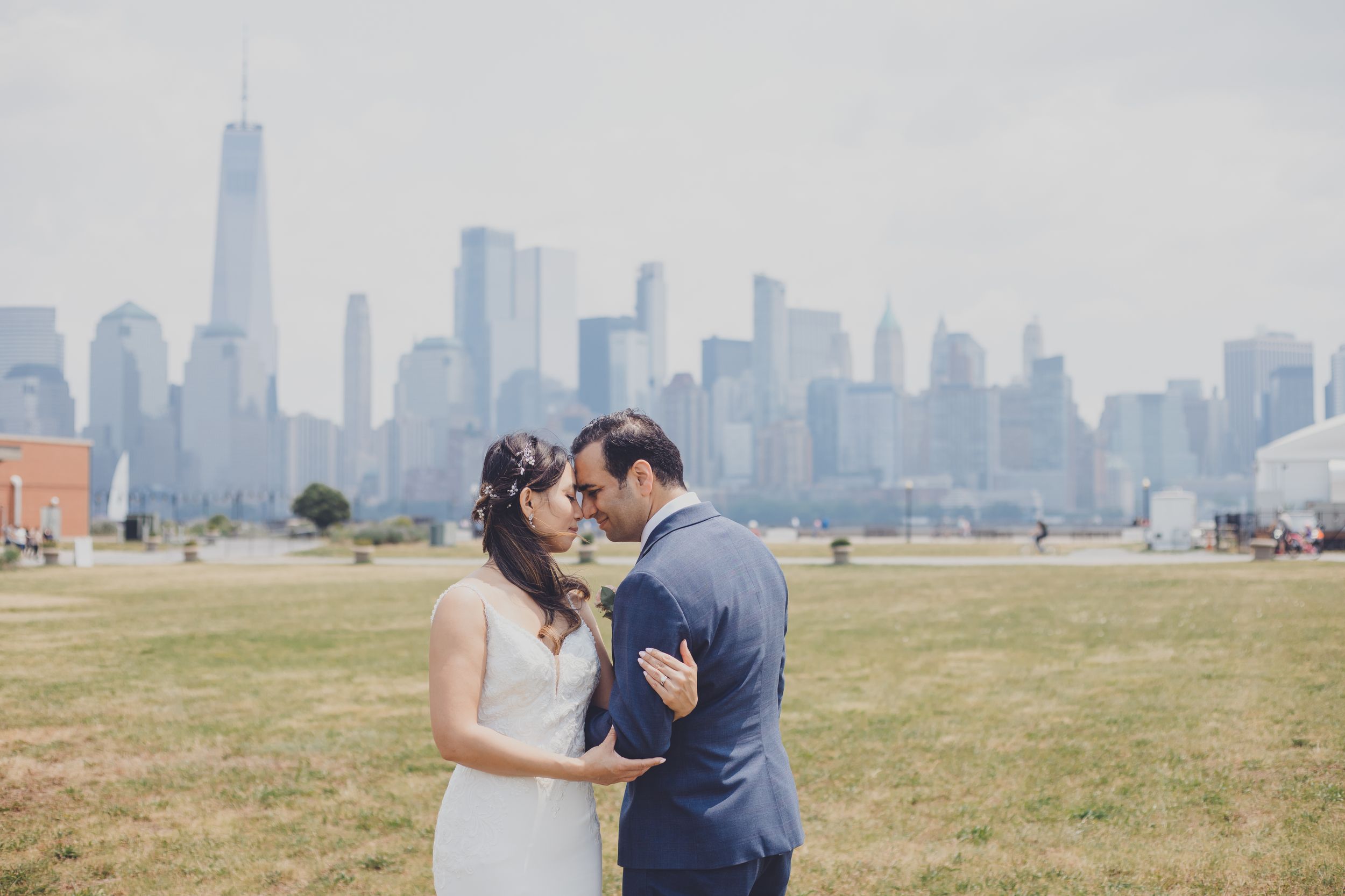 A joyful wedding couple showing their rings to the camera in an outdoor garden setting.