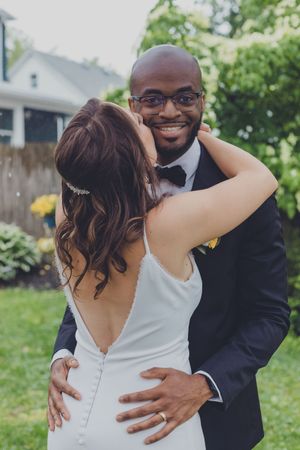 A candid wedding moment captured on a front porch with French doors in the background.