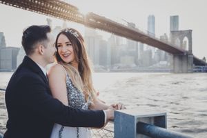 A couple shares an intimate moment on a rooftop with a city skyline backdrop.