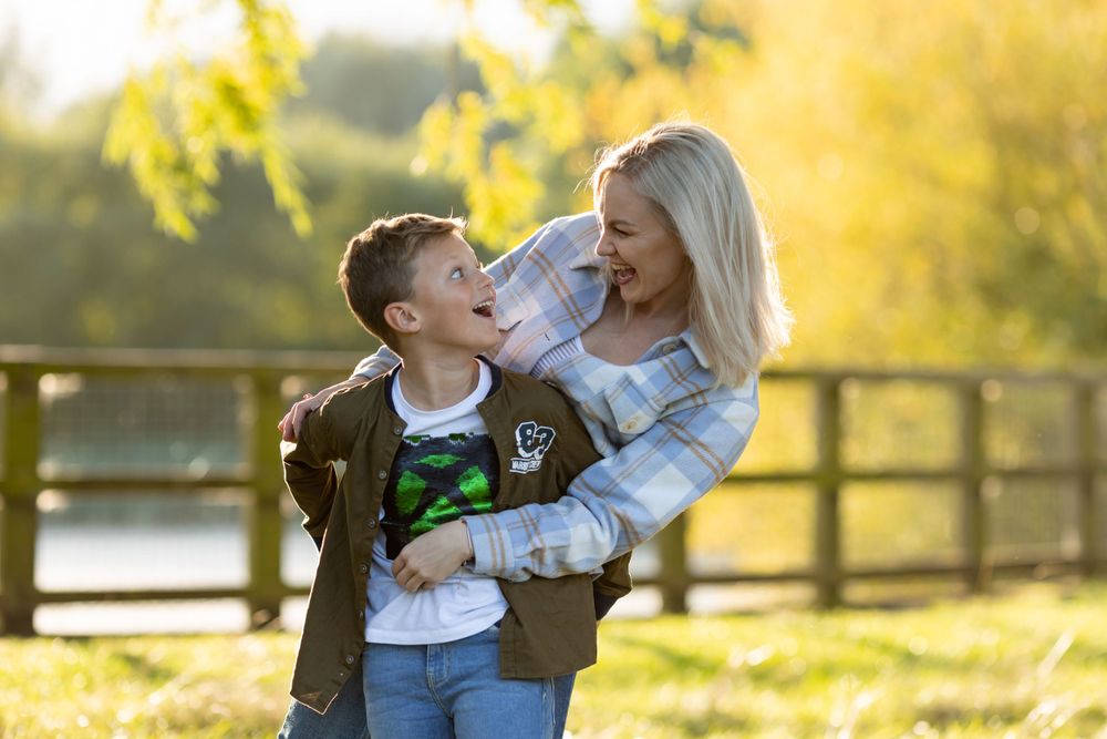 Mother and son share a joyful moment together outdoors in autumn setting.