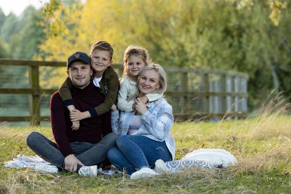 Family cuddles together on blanket for casual outdoor portrait session.