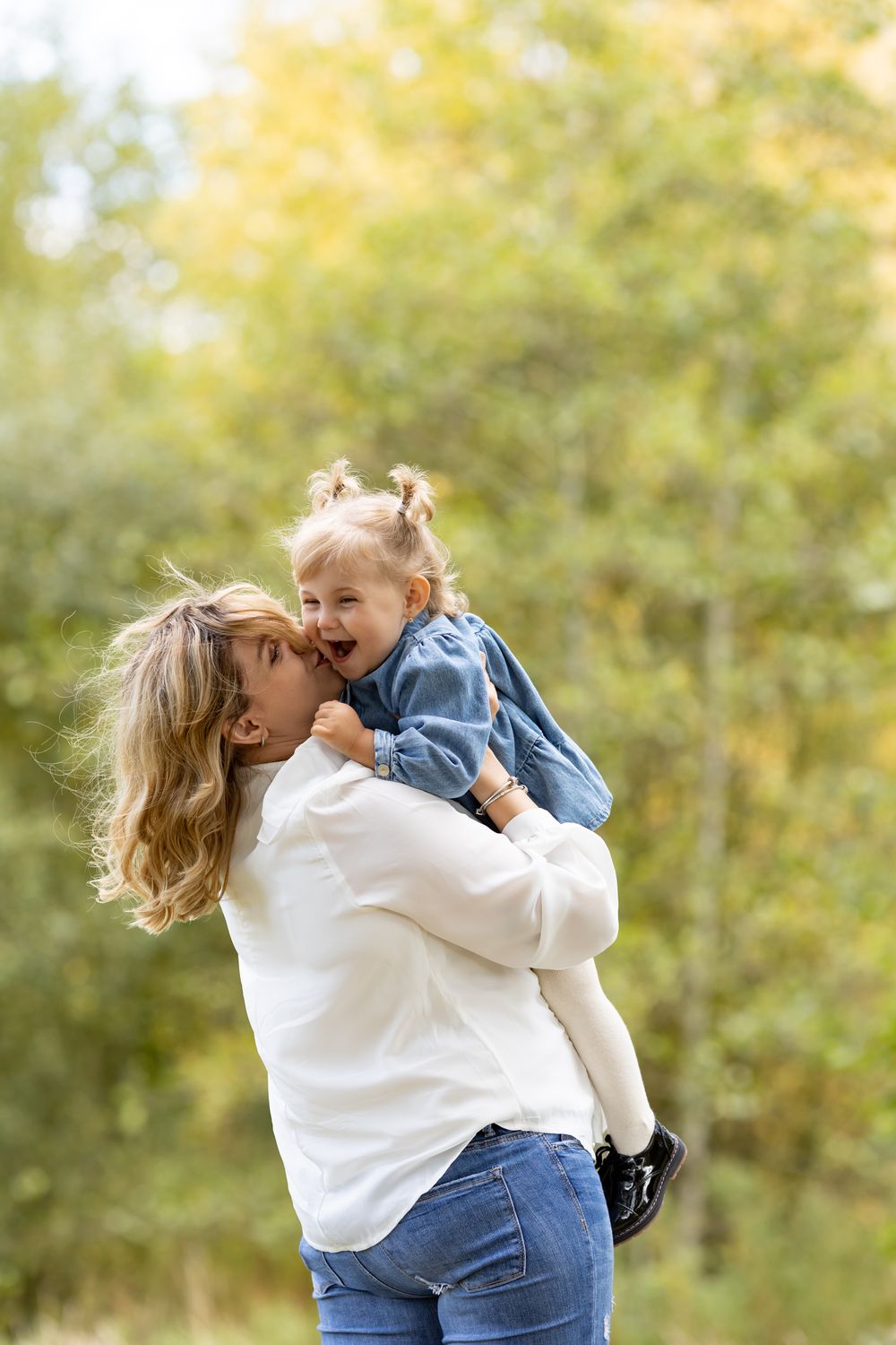 A heartwarming outdoor moment between parent and child with autumn foliage in the background.