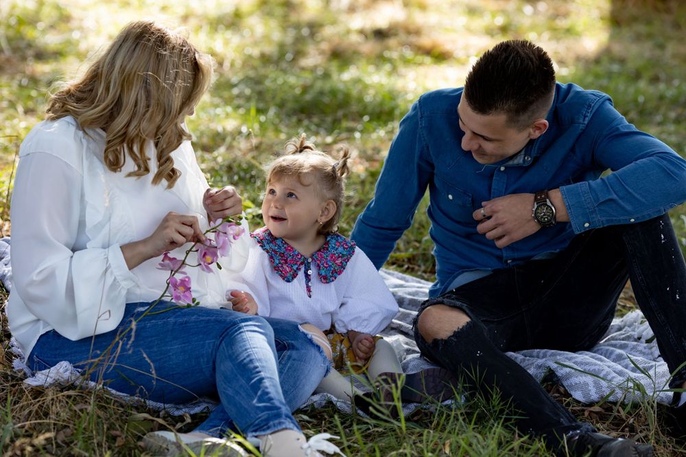 Family sits together on grass having a tender moment during an autumn photoshoot.