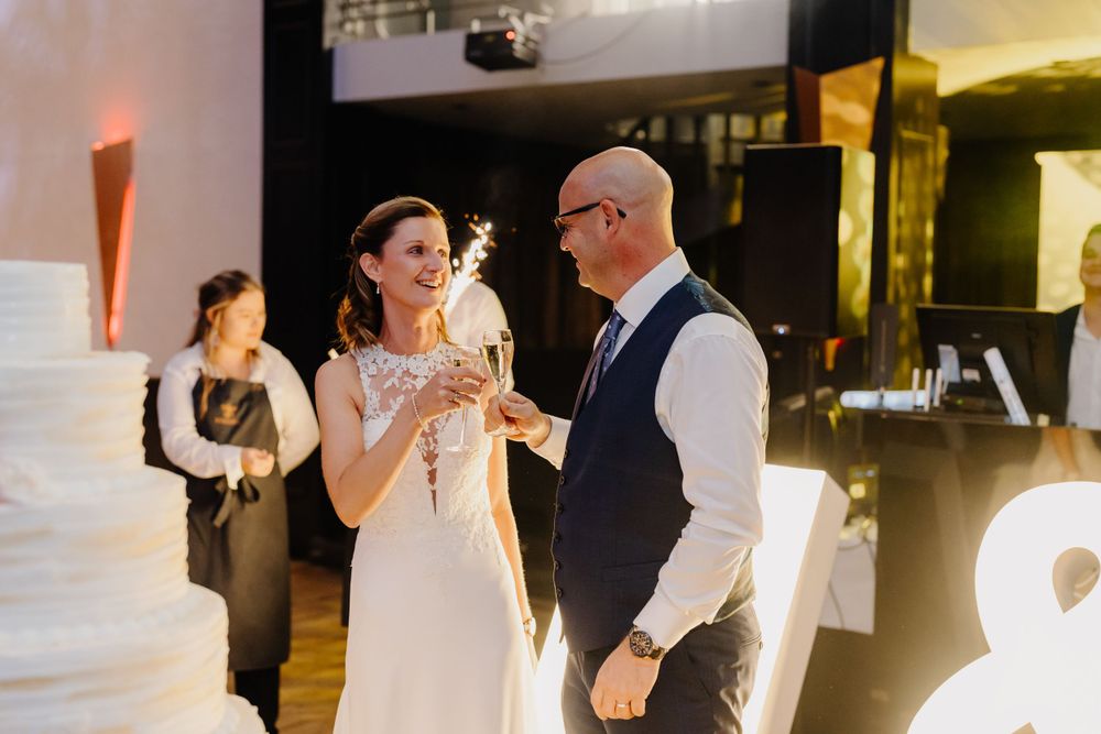 At an elegant wedding reception, a bride and groom share a joyful moment while talking on the dance floor.