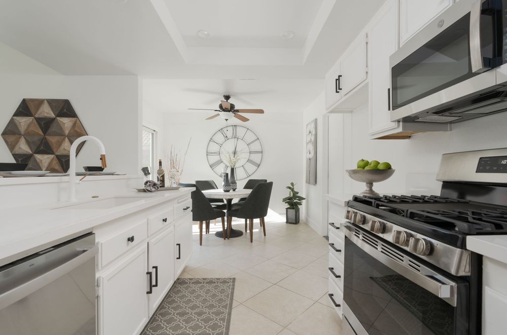 Modern white kitchen with stainless steel appliances and geometric wall art.