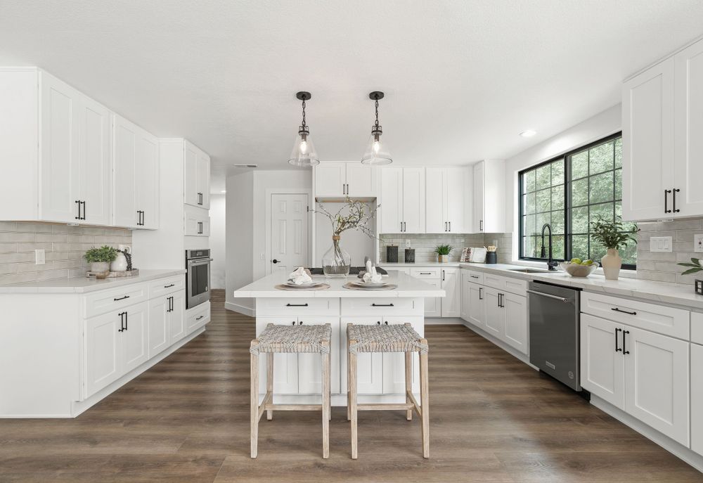 Spacious white kitchen with center island, pendant lights and hardwood floors in modern farmhouse style.