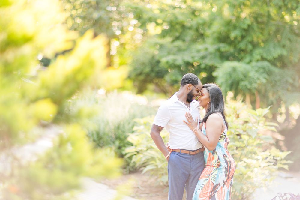 Romantic sunlit engagement photo in a lush garden setting.