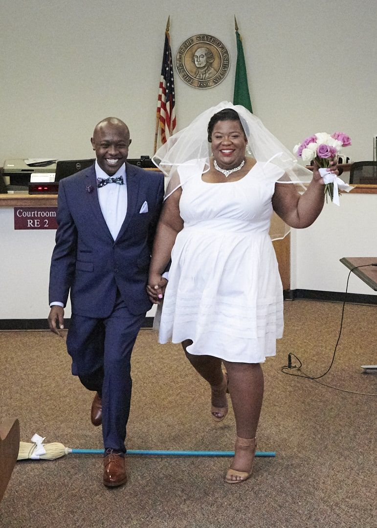 Bride and groom jumping over broom at Redmond Courthouse in Redmond, WA