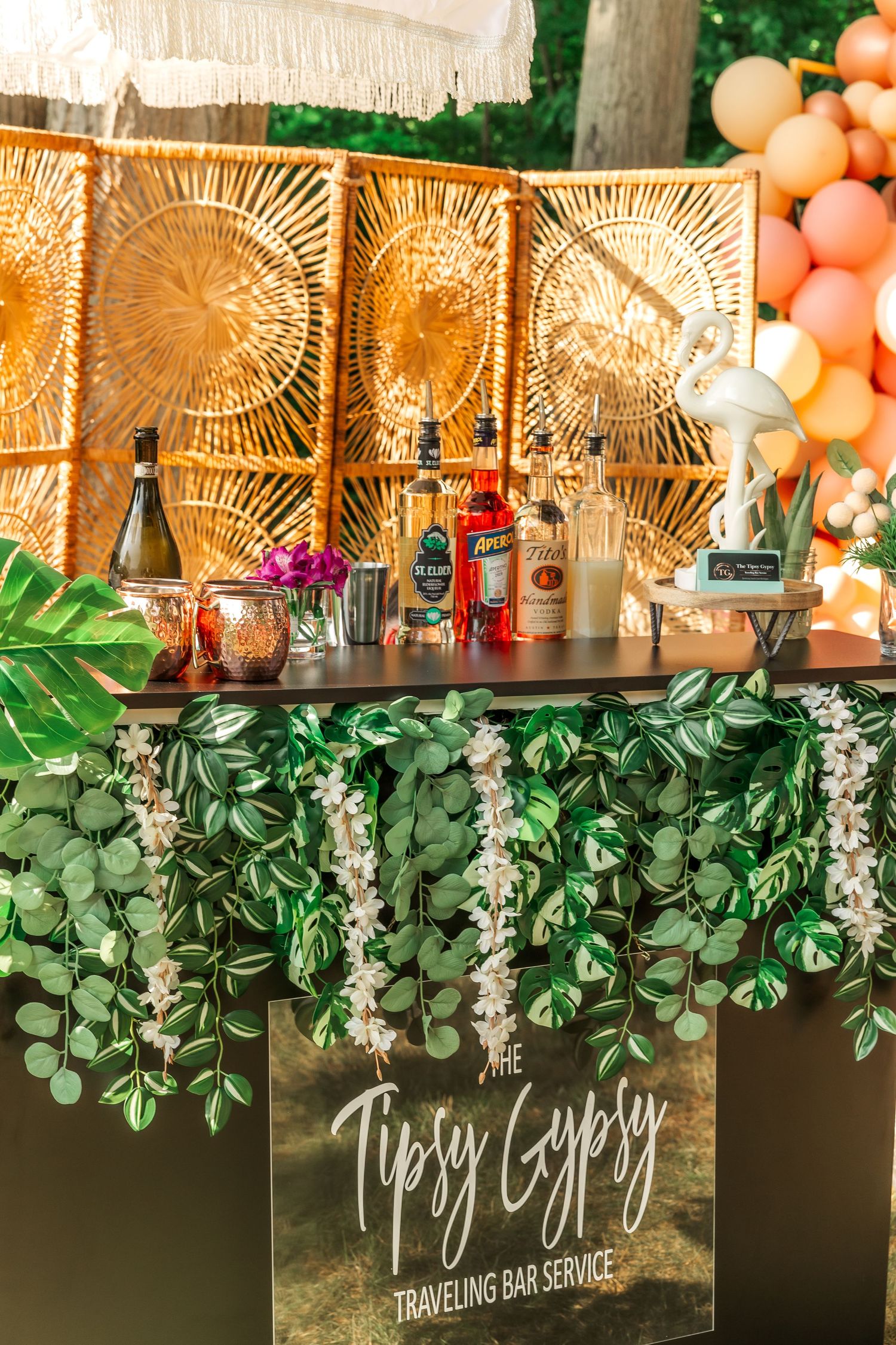 Mobile bar station with gold sunburst backdrop, hanging greenery, and tipsy gypsy signage.