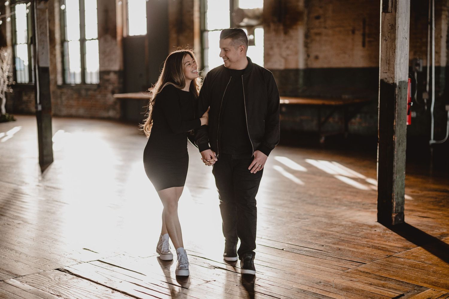 Couple walking together in a rustic industrial venue with exposed brick walls.