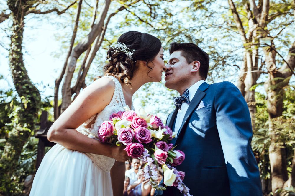 Romantic wedding portrait with colorful bouquet against natural outdoor backdrop.