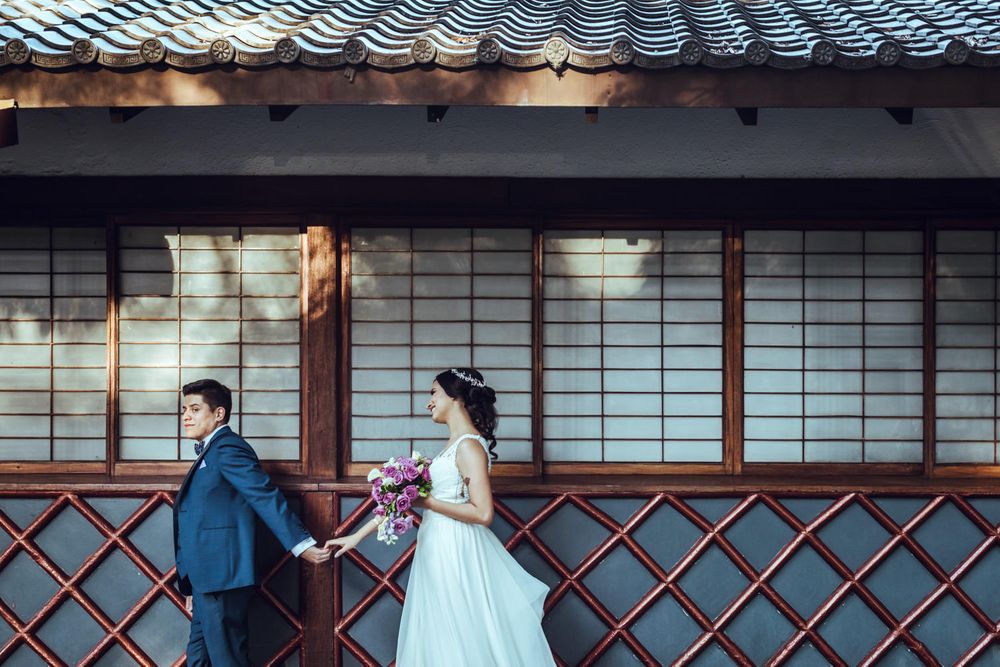Wedding couple poses by traditional Japanese sliding doors and lattice work.