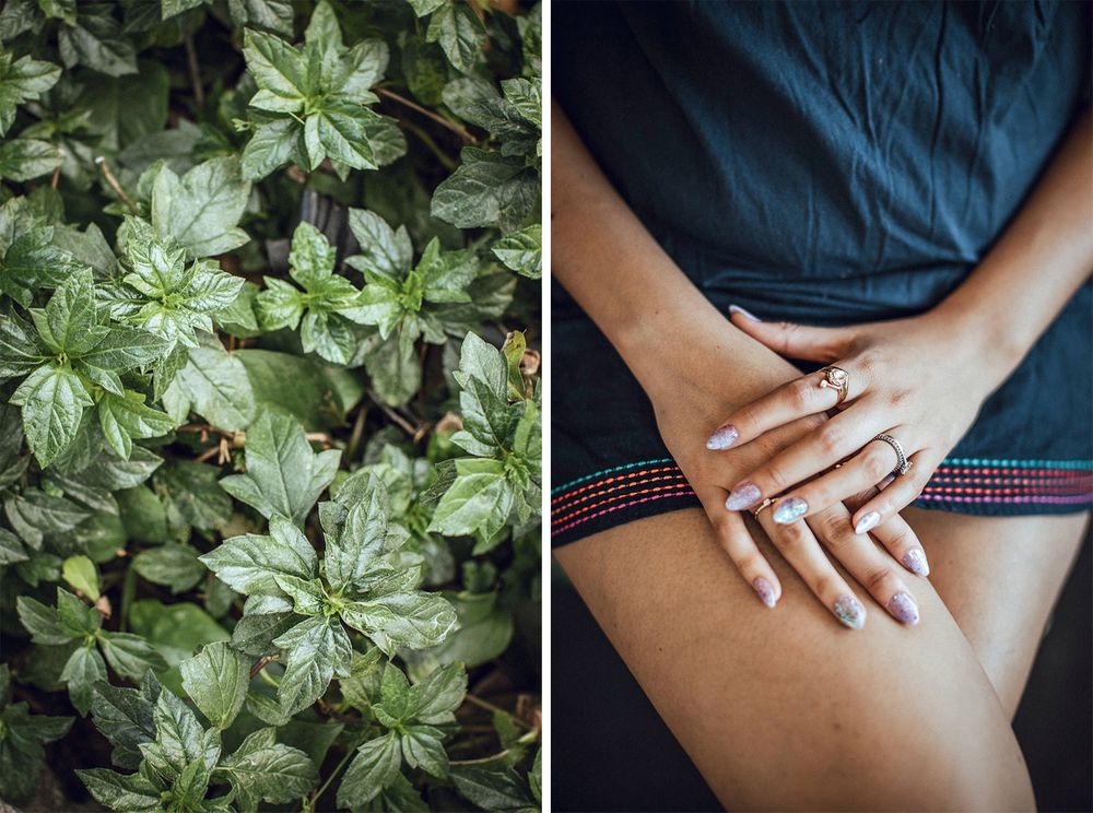 Close-up of hands with a wedding ring resting on a lap next to lush green foliage.