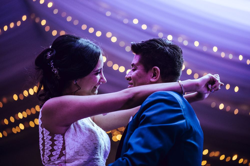 A couple dancing intimately under romantic lighting at an elegant wedding reception venue.