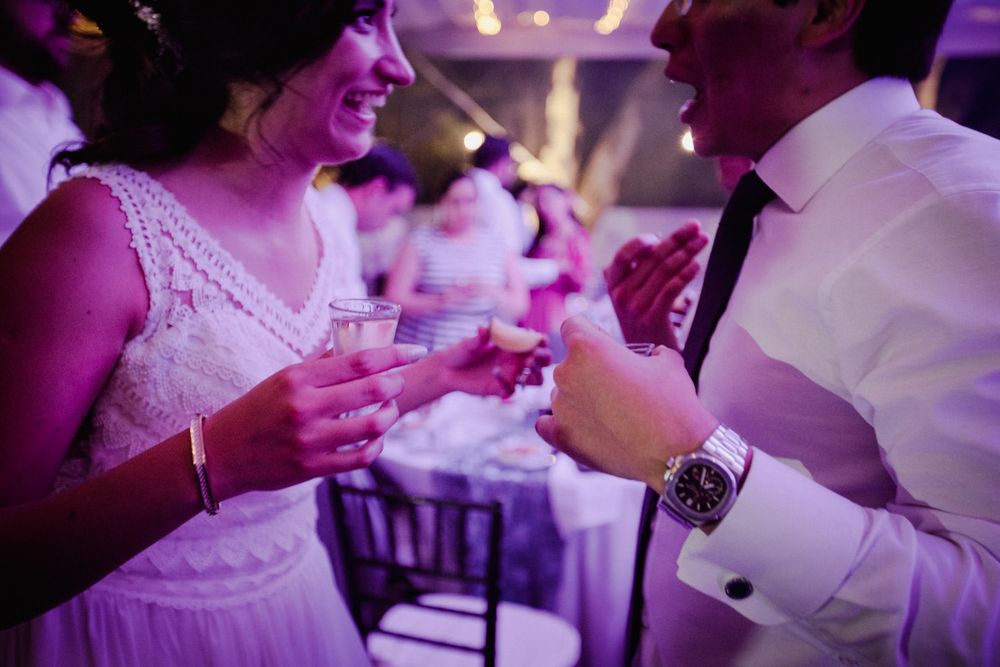 Wedding guests share drinks and conversation during an evening reception.