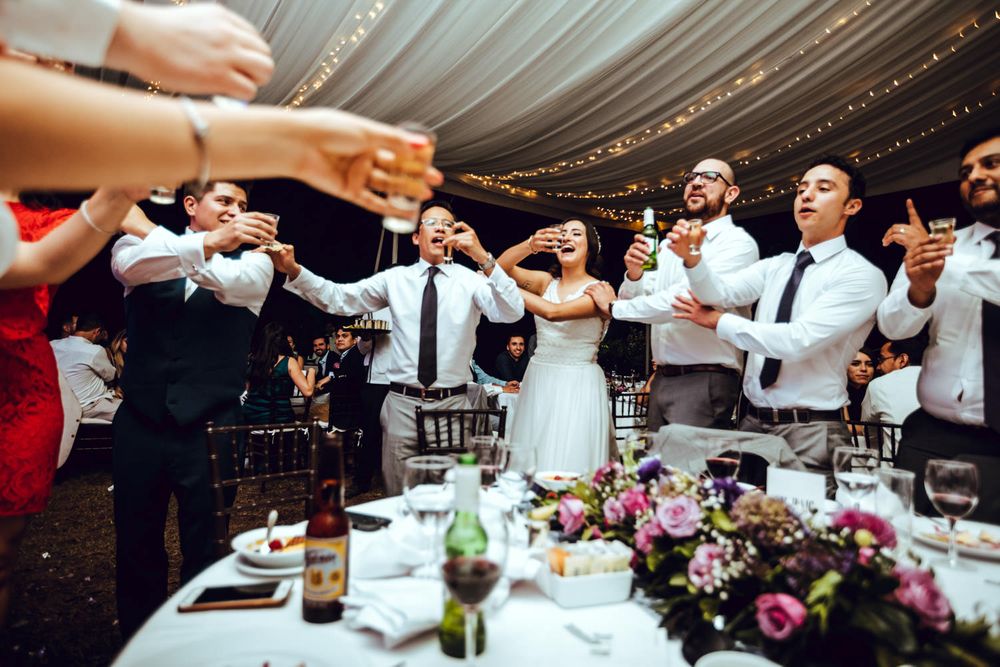 Wedding guests and newlyweds raise their glasses in a celebratory toast at the reception.