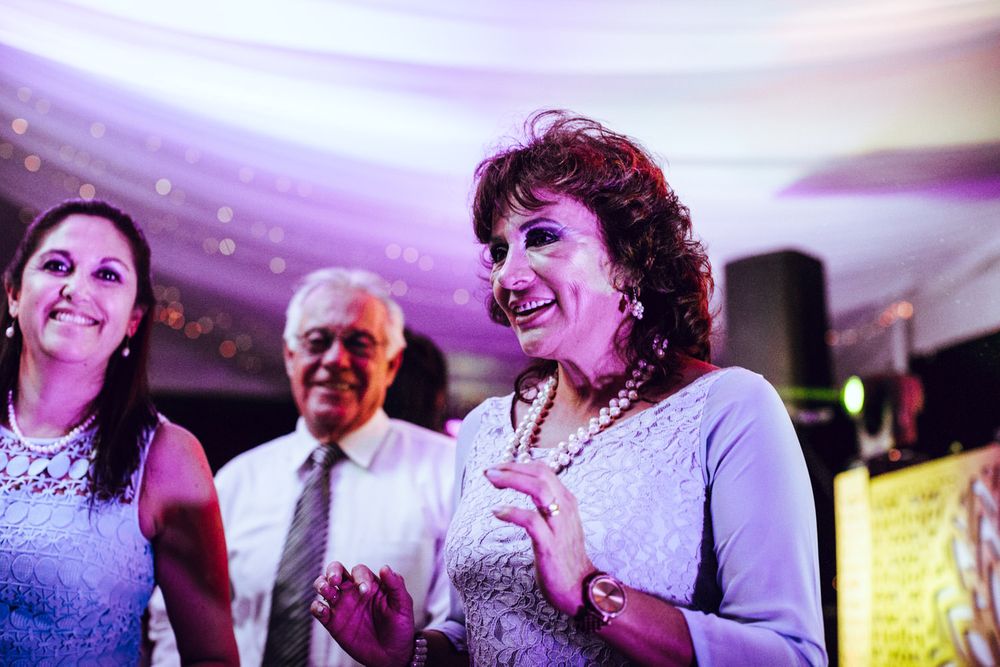 Wedding guests dancing and enjoying themselves under purple ambient lighting.