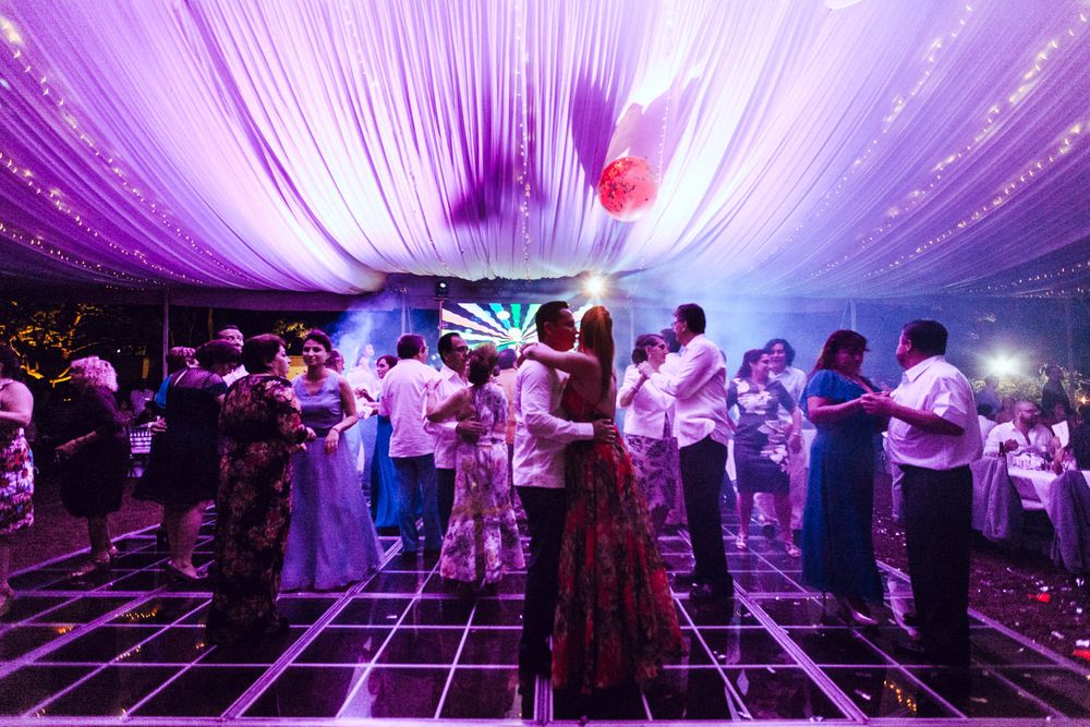 Dance floor filled with couples slow dancing under dramatic purple lighting and draped fabric decor.