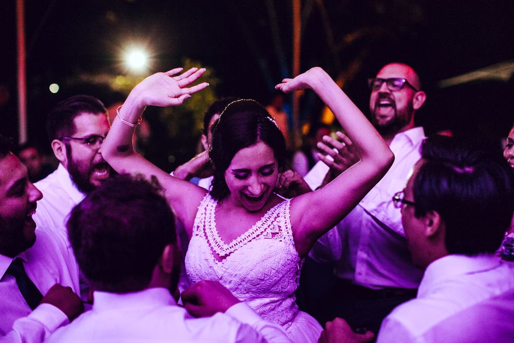 Wedding reception dance floor filled with energetic guests celebrating under purple lighting.
