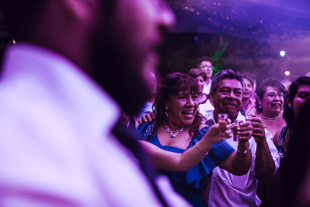 Party crowd enjoying themselves under purple mood lighting at an evening celebration.