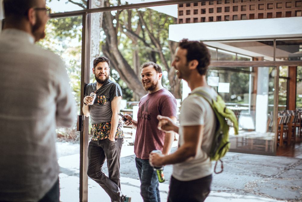 A group having an animated conversation outside a building with lattice windows.