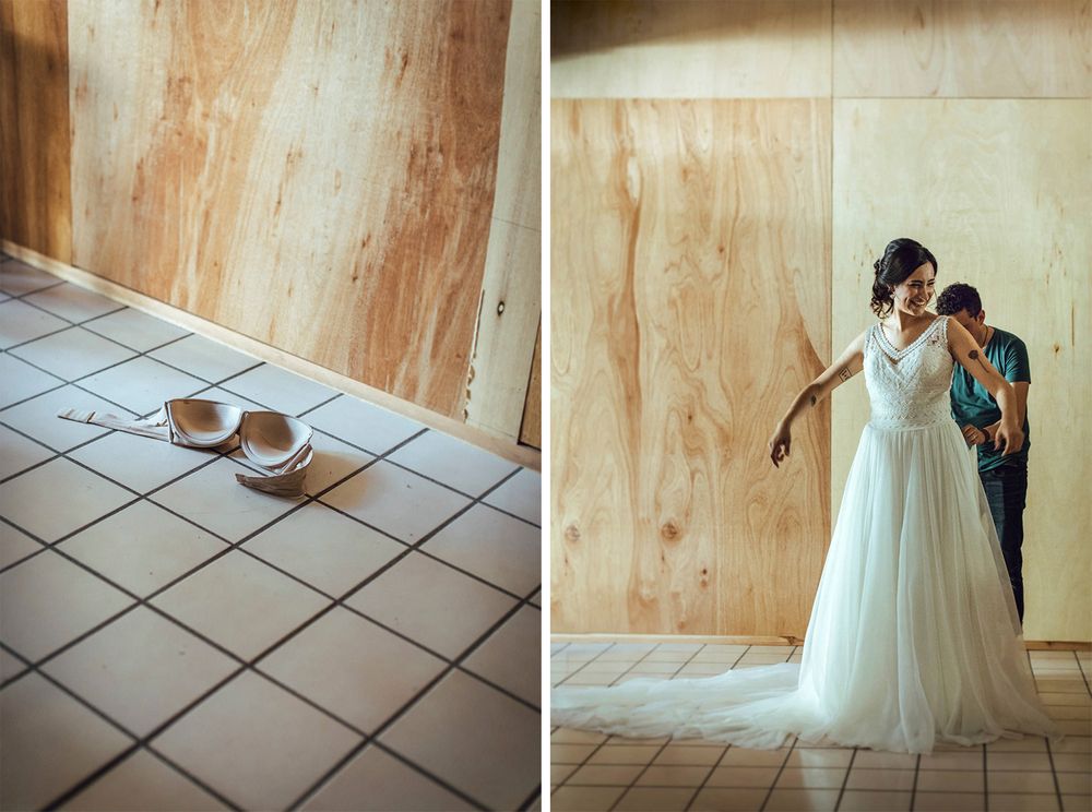 Wedding dress and shoes arranged on tiled floor against wooden wall for preparation.