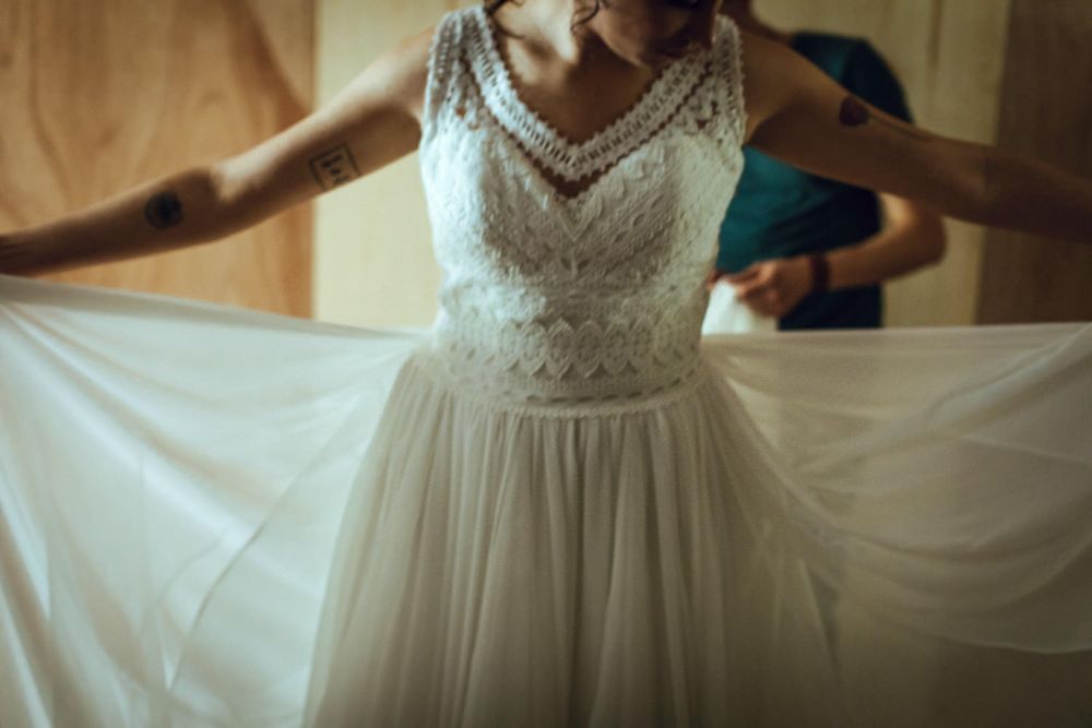 Close-up detail of an elegant lace wedding dress with flowing tulle skirt.