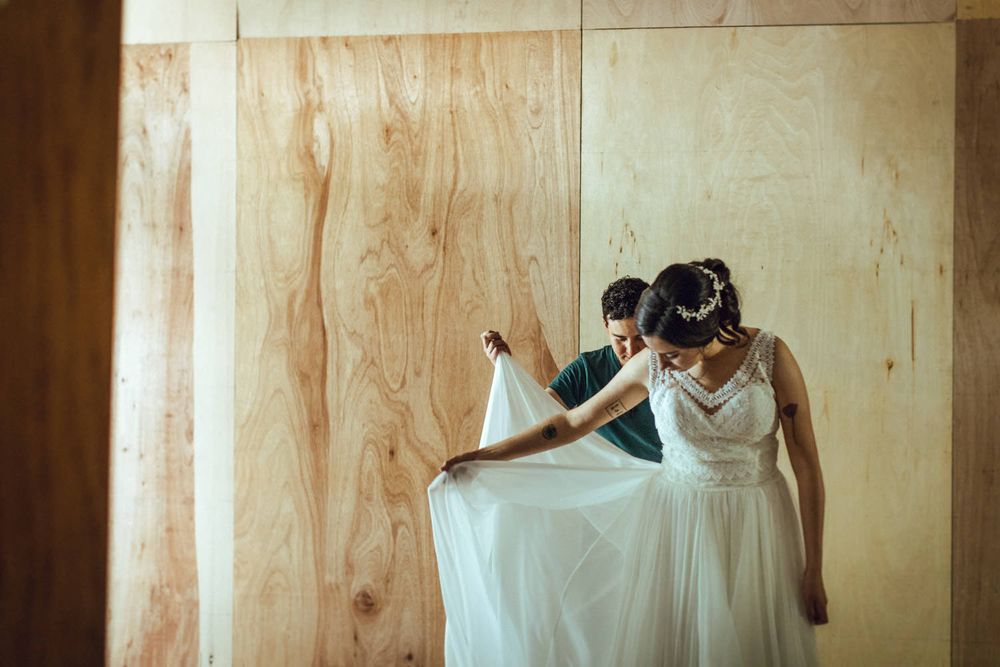 Wedding dress preparation scene against light wooden wall panels.