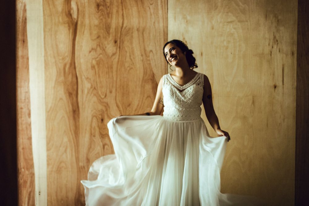 Elegant wedding dress with lace bodice and flowing tulle skirt against wooden backdrop.