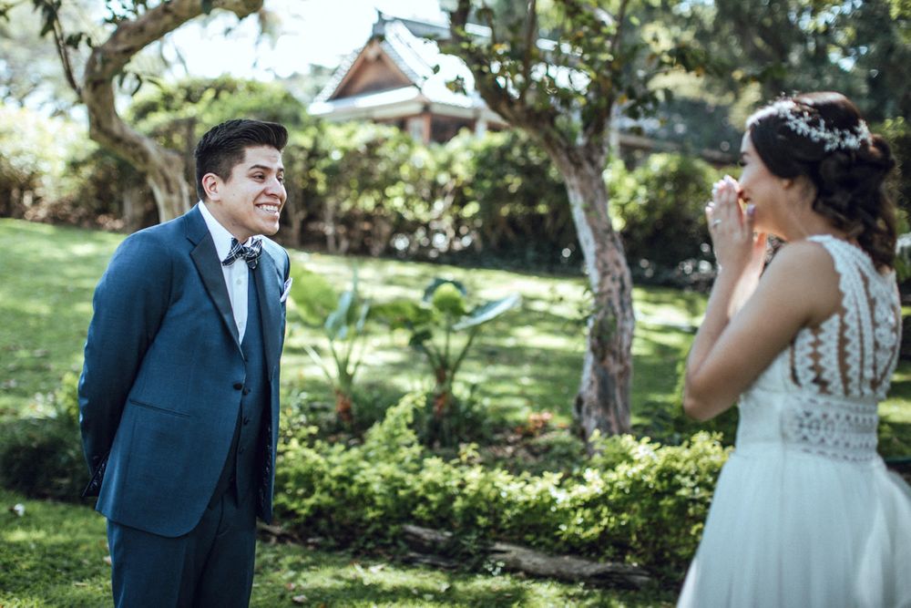 A candid first look moment between newlyweds in a garden setting with natural lighting.