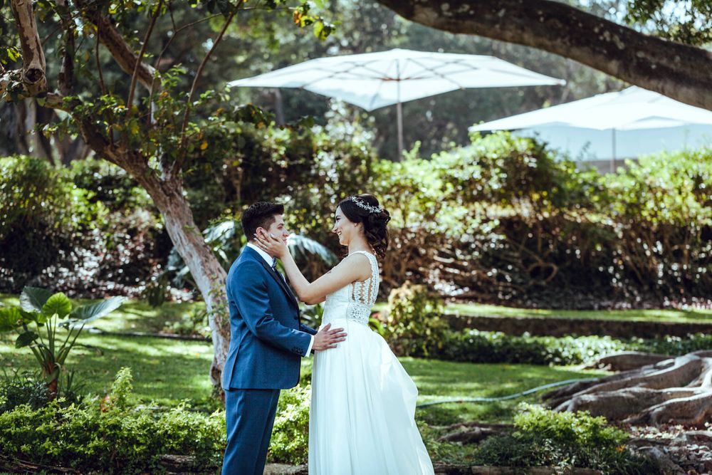 A couple dancing together in a sunlit garden with white umbrellas in the background.