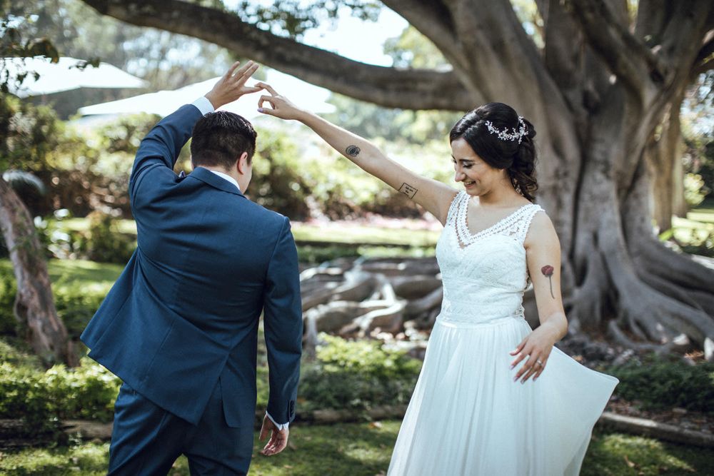 A couple sharing a romantic dance under a large tree in an outdoor garden setting.