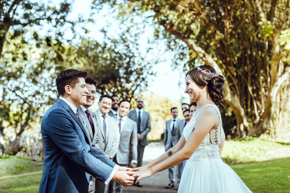 Outdoor wedding ceremony setup with couple exchanging vows under sunlit trees.