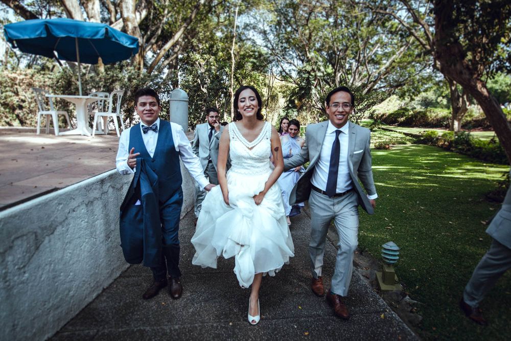 Wedding party running and laughing together on outdoor path during photo session.