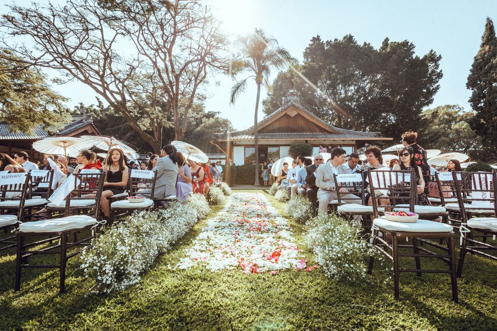 Beautiful outdoor wedding ceremony setup with white chairs and floral arrangements in a sunny garden setting.