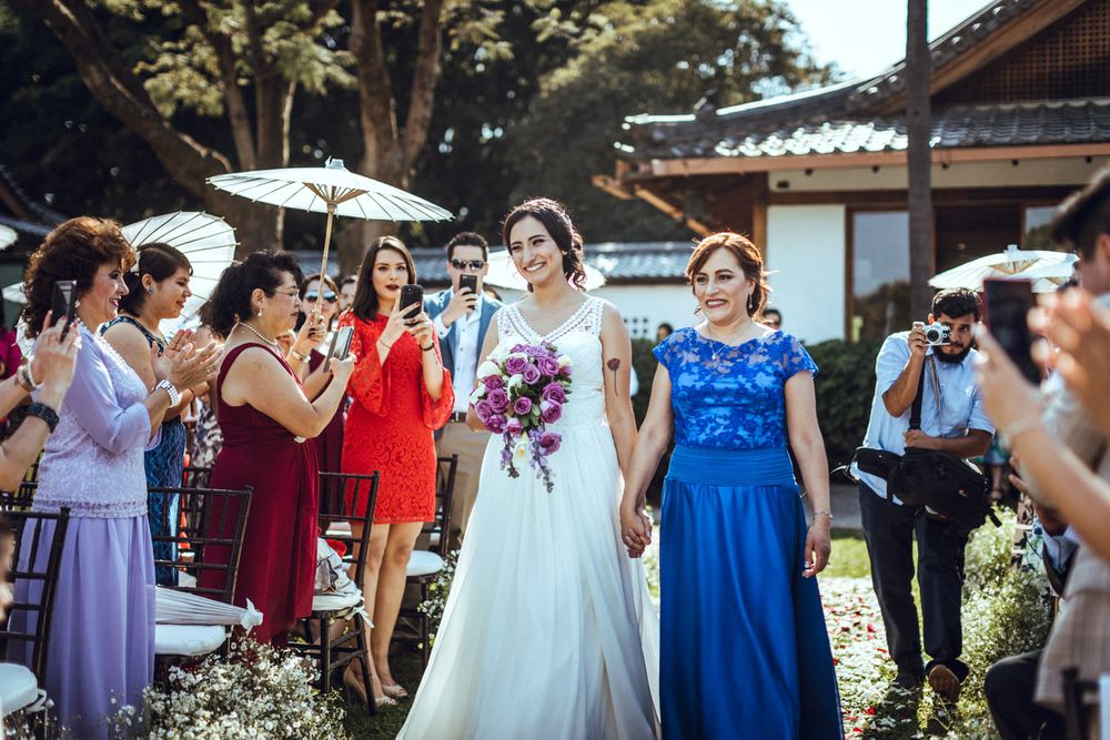Wedding party dressed in blue and purple bridesmaid dresses poses outdoors with the bride in white.