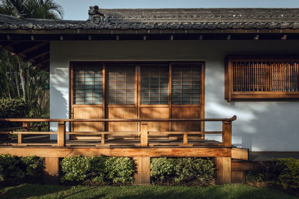 Modern Japanese style house exterior with wooden deck and sliding glass doors.