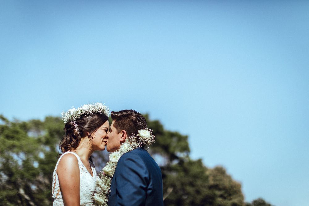 A romantic moment captured between newlyweds against a blue sky background.